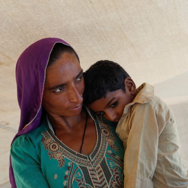 A woman who became displaced following rains and floods during the monsoon season holds her child while standing outside her tent in Sehwan, Pakistan, Sept. 13, 2022. (OSV News photo/Akhtar Soomro, Reuters)