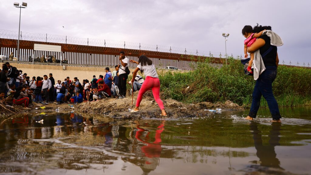 Mensaje de obispo Seitz sobre la migración: Migrantes que buscan asilo en Estados Unidos se reúnen cerca de una valla de alambre el 12 de septiembre de 2023, mientras miembros de la Guardia Nacional de Texas permanecen a la espera para impedir que los migrantes entren en Estados Unidos después de cruzar el Río Bravo desde México. (Foto de OSV News/Jose Luis Gonzalez, Reuters)