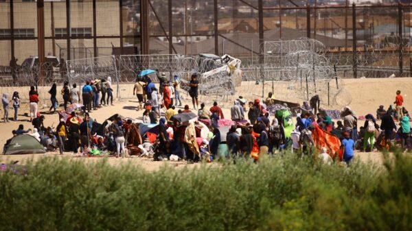 Migrantes son vistos desde Ciudad Juárez, México, mientras se reúnen cerca del muro fronterizo de EE.UU. el 24 de septiembre de 2023, después de cruzar el Río Grande con la intención de entregarse a los agentes de la Patrulla Fronteriza de EE.UU. para solicitar asilo. (Foto OSV News/Jose Luis Gonzalez, Reuters)