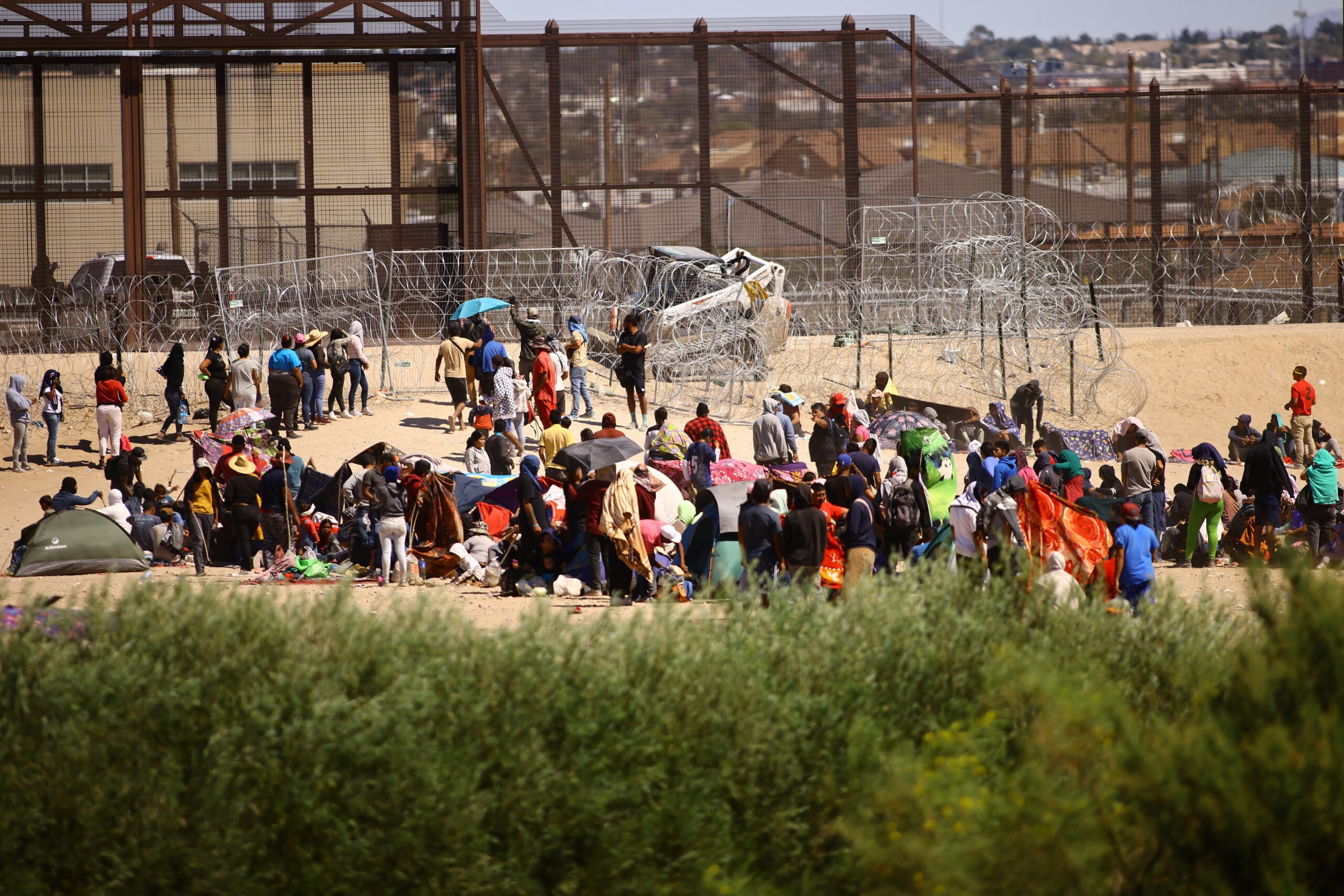 Migrantes son vistos desde Ciudad Juárez, México, mientras se reúnen cerca del muro fronterizo de EE.UU. el 24 de septiembre de 2023, después de cruzar el Río Grande con la intención de entregarse a los agentes de la Patrulla Fronteriza de EE.UU. para solicitar asilo. (Foto OSV News/Jose Luis Gonzalez, Reuters)