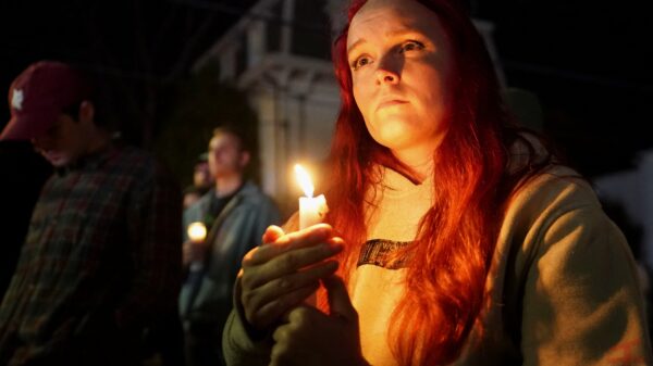 A woman holds a candle outside the Basilica of Sts. Peter and Paul in Lewiston, Maine, Oct. 29, 2023, during a vigil for the victims of a deadly mass shooting. Robert Card, who later took his own life, shot and killed 18 people and injured 13 others at a restaurant and a bowling alley in Lewiston Oct. 25. (OSV News photo/Kevin Lamarque, Reuters)
