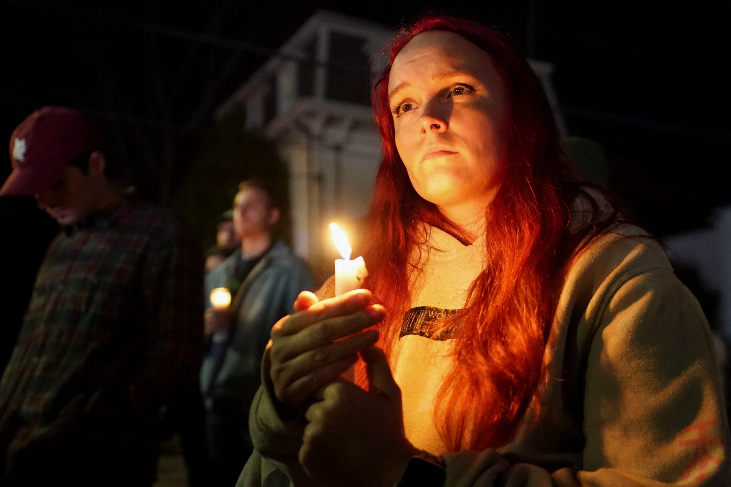 A woman holds a candle outside the Basilica of Sts. Peter and Paul in Lewiston, Maine, Oct. 29, 2023, during a vigil for the victims of a deadly mass shooting. Robert Card, who later took his own life, shot and killed 18 people and injured 13 others at a restaurant and a bowling alley in Lewiston Oct. 25. (OSV News photo/Kevin Lamarque, Reuters)