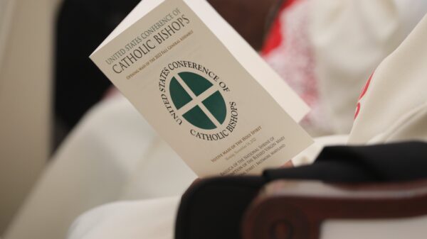 File photo of a bishop holding a program during Mass at the Basilica of the National Shrine of the Assumption of the Blessed Virgin Mary Nov. 14, 2022. The U.S. bishops began their fall plenary assembly in Baltimore Nov. 13, 2023, with a Mass for peace. The two public days of the USCCB assembly, Nov. 14 and 15, promised a packed agenda for the bishops. (CNS photo/Bob Roller)