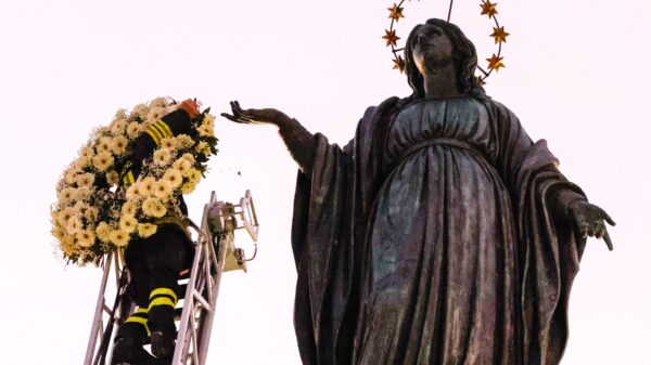 A firefighter places a wreath of flowers on a Marian statue overlooking the Spanish Steps in Rome Dec. 8, 2023, the feast of the Immaculate Conception. Pope Francis was to pray at the statue later in the day, continuing the papal tradition of visiting the Spanish Steps on the feast of the Immaculate Conception. (CNS photo/Lola Gomez)