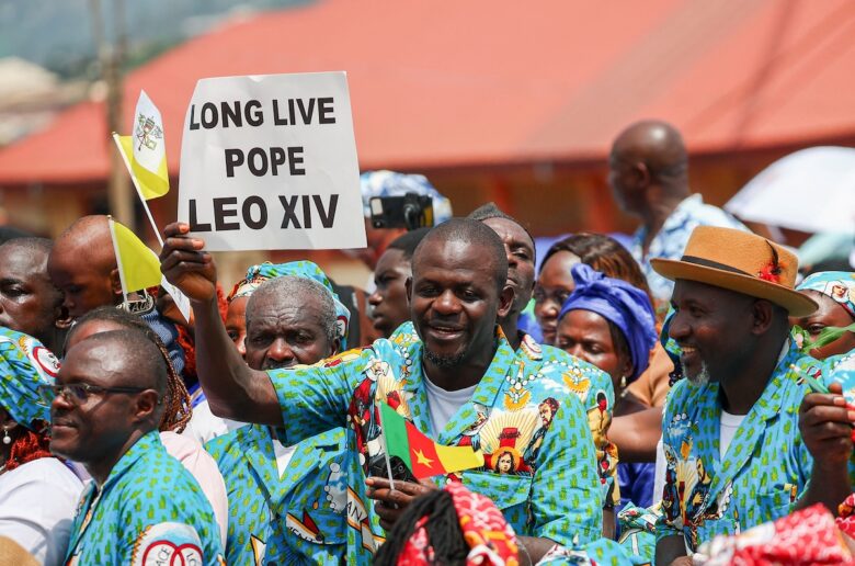 A man holds a sign as people gather outside St. Joseph's Cathedral in Bamenda, Cameroon, April 16, 2026, as they wait for the arrival of Pope Leo XIV for a Meeting for Peace. (OSV News photo/Guglielmo Mangiapane, Reuters)