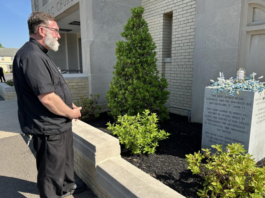 Father Christopher Walsh, pastor of St. Cecilia Parish in Philadelphia, is seen May 18, 2026, contemplating a memorial to clergy abuse survivors he recently dedicated. Father Walsh told OSV News he was inspired to create the display after learning the history of the parish, which featured in a 2005 Philadelphia grand jury report, and after burying one of the victims of a now-deceased former priest who once was assigned to the parish. (OSV News photo/Gina Christian)
