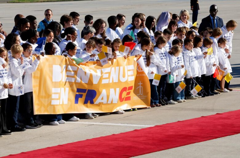 Children with flags and a banner gather to welcome Pope Leo upon his arrival at Paris-Orly Airport in Orly, near Paris, for a four-day apostolic journey to France, Sept. 25, 2026. (OSV News photo/Remo Casilli, Reuters)